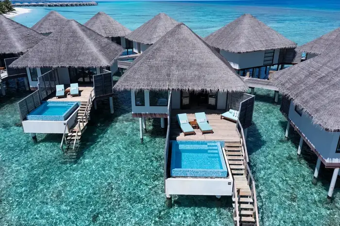 The beach half of a split stay — a beach villa bedroom opening onto a private plunge pool and tropical garden