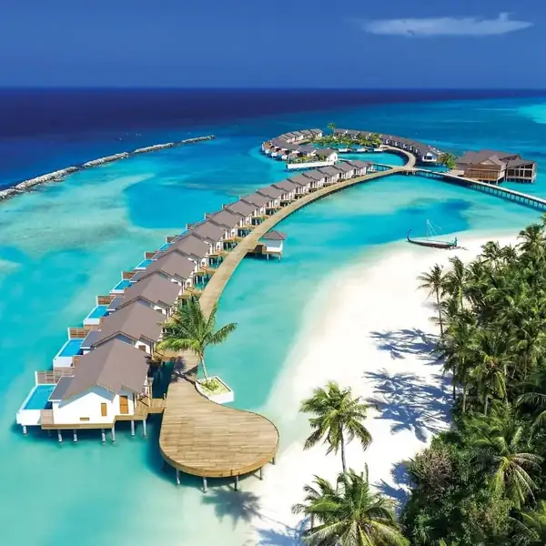 Aerial view of a Maldives island with overwater villas curving into a turquoise lagoon