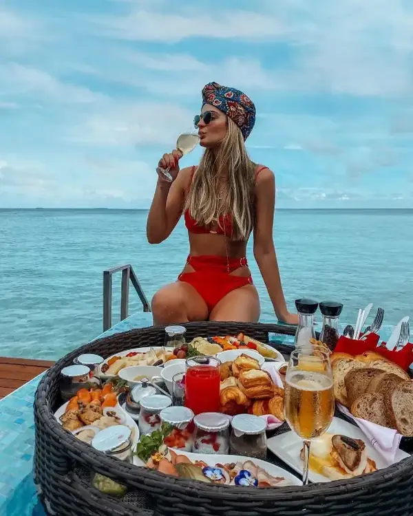 A woman enjoying a floating breakfast in a private pool overlooking the ocean