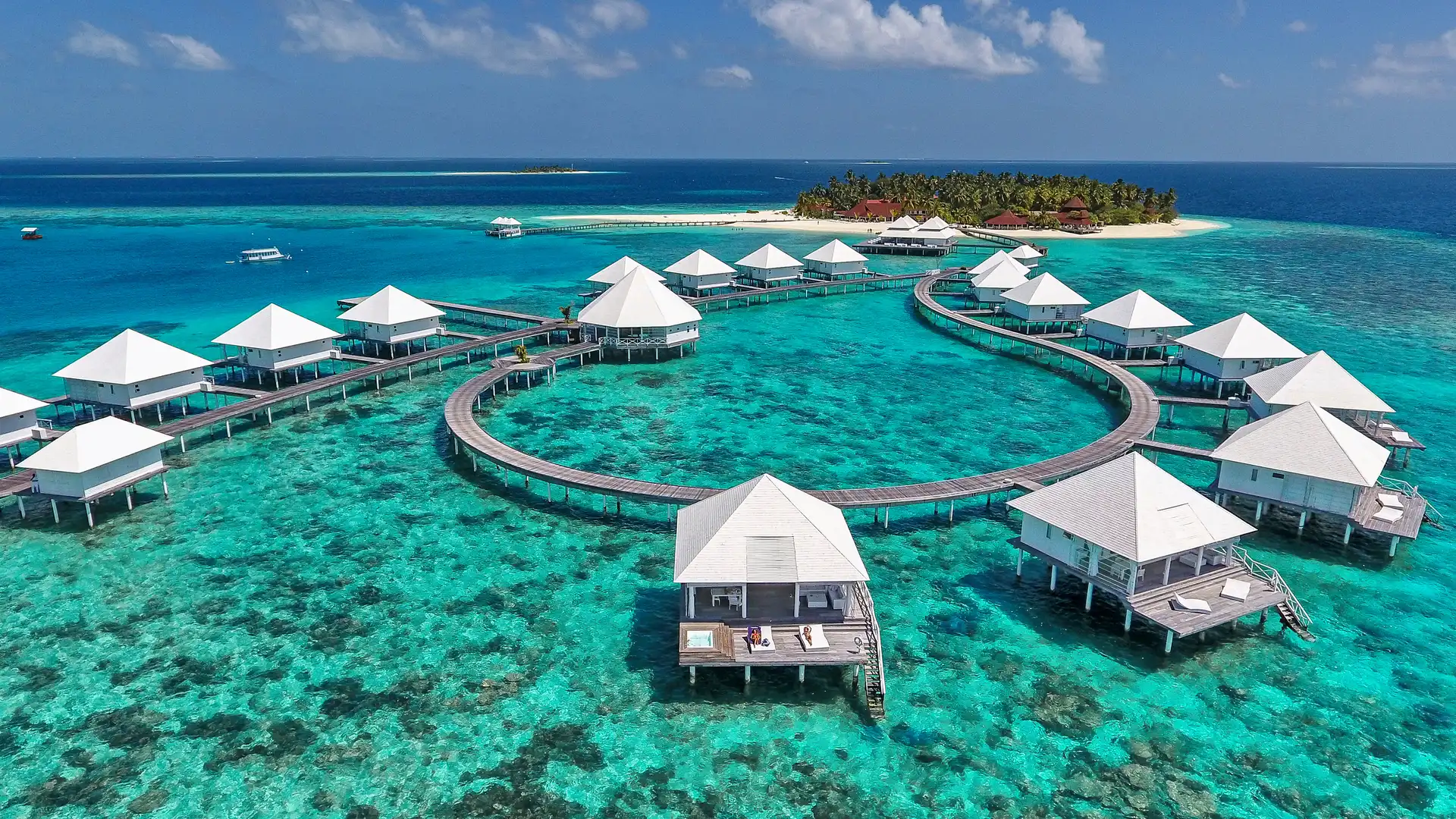 Aerial view of a row of overwater villas on a private island surrounded by turquoise lagoon in the Maldives